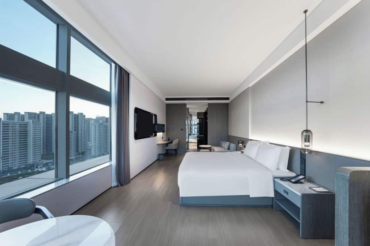 Una habitación de hotel moderna con una cama grande, un escritorio, una silla y un televisor.