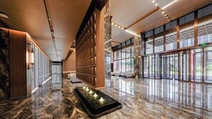 A spacious lobby with a marble floor, wooden paneling, and large windows allowing natural light. - KEEJOY HOTEL (Fuzhou)