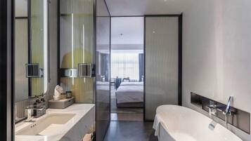 A modern hotel bathroom with a large bathtub, two sinks, and a large mirror.