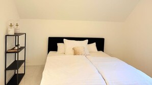 A bedroom with a bed, a black headboard, and a black shelving unit against the wall. - Luxrem 5 Apartments Skyline (Biel)