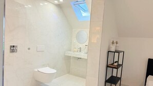 A modern bathroom with a skylight, a bathtub, a toilet, and a vanity with a mirror. - Luxrem 5 Apartments Skyline (Biel)