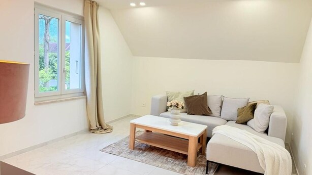 A modern living room with a sofa, a coffee table, and a window with curtains. - Luxrem 5 Apartments Skyline (Biel)