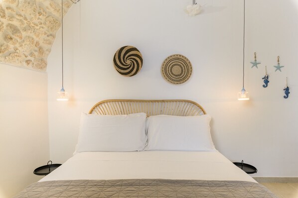A bed with a woven headboard, two white pillows, a quilted blanket, and a wall with decorative woven items and starfish ornaments.