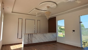 A spacious room with a marble reception desk, a ceiling fan, and a large window offering a view of the outdoors. - Orchard Hills Resorts (Pushkar)
