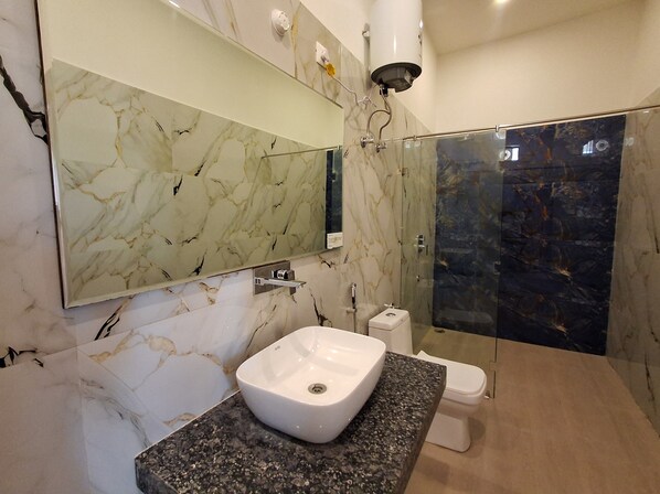 A bathroom with a marble sink, a toilet, and a shower area. - Orchard Hills Resorts (Pushkar)