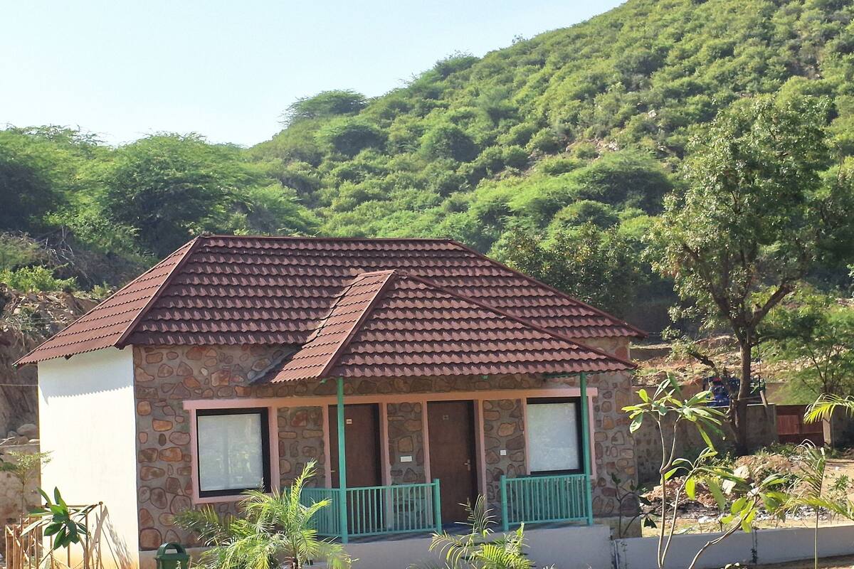 A small stone building with a tiled roof, a window, and a porch with a railing.