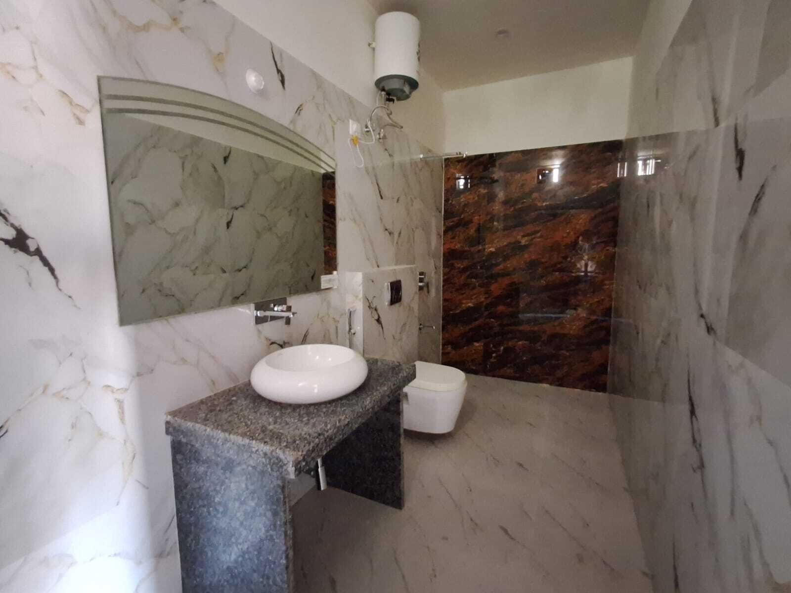 Een badkamer met een marmeren wastafel, toilet en douche.