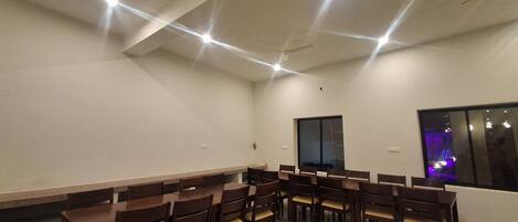 A conference room with a long table and chairs, a large window, and a ceiling light fixture.