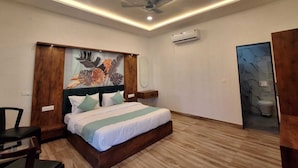 A modern bedroom with a bed, a ceiling fan, an air conditioning unit, and a wooden floor. - Orchard Hills Resorts (Pushkar)