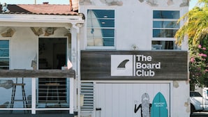 A building with a sign reading "The Board Club" and a surfboard graphic. - Solarena at Newport Beach (Newport Beach)