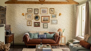 A cozy living room with a brown leather sofa, a smaller grey sofa, and a coffee table with books. - Chapman House - 3 Bedroom City Centre Retreat (Norwich)