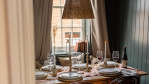 A dining table set for four with candles, wine glasses, and a bottle of wine. - Chapman House - 3 Bedroom City Centre Retreat (Norwich)