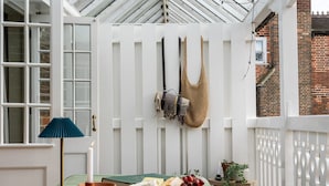 A conservatory with a green-striped table, a lamp, a book, cheese, grapes, and a woven bag. - Chapman House - 3 Bedroom City Centre Retreat (Norwich)