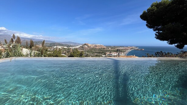 Ein freier Blick auf einen Pool mit einer schönen Landschaft im Hintergrund, einschließlich einer Küstenlinie und fernen Bergen.