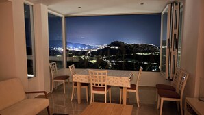 Ein Essbereich mit Blick auf eine beleuchtete Stadtlandschaft bei Nacht.