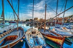 A marina with multiple boats docked, surrounded by buildings and a clear sky. - Affittimoderni La Maddalena - MADA39 (La Maddalena)