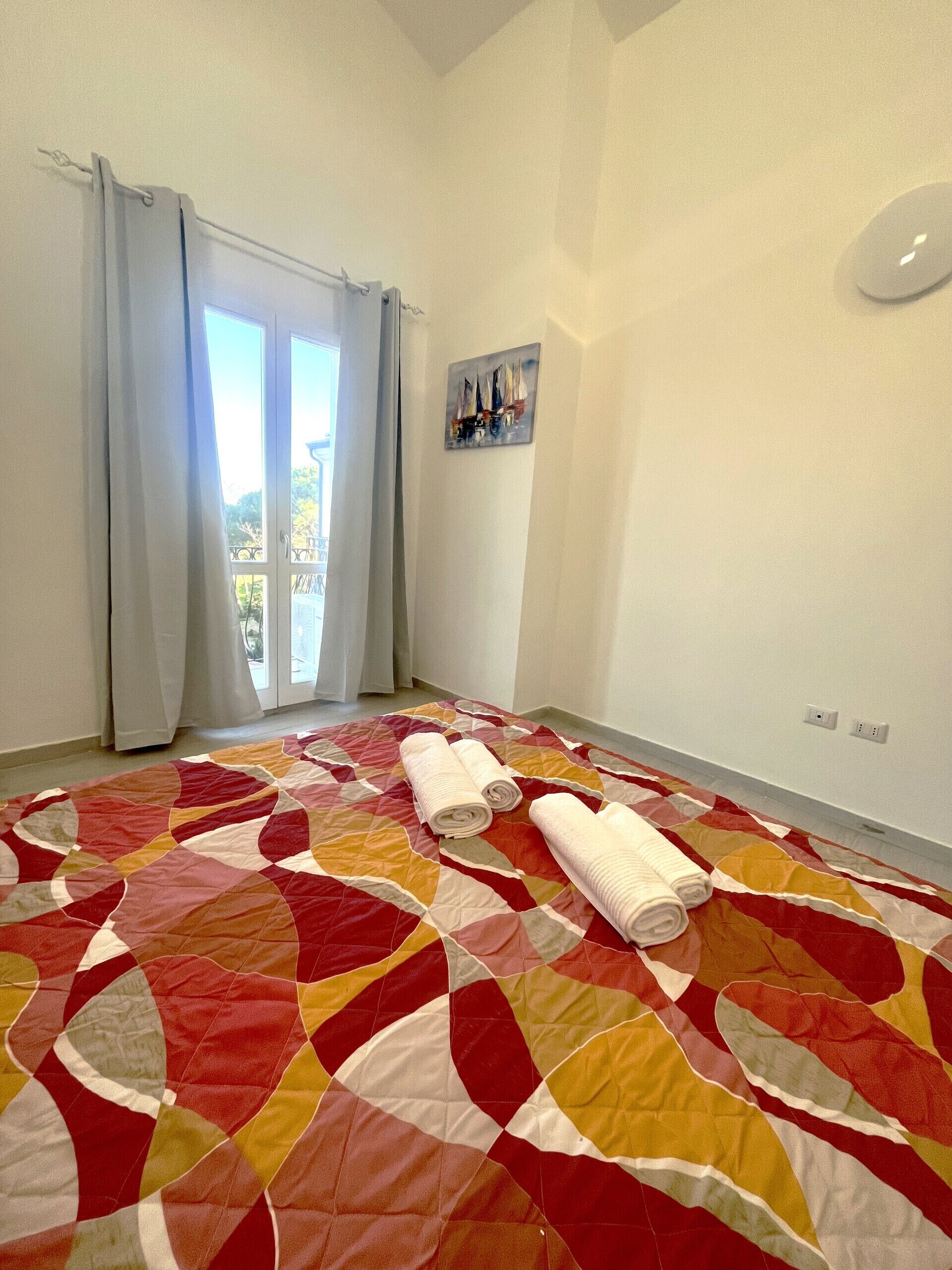 Une chambre d’hôtel avec un grand couvre-lit matelassé, un tableau au mur et une vue par la fenêtre.