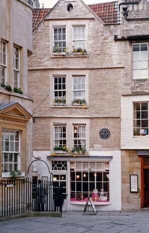 A traditional stone building with multiple windows, a signboard, and a small awning over the entrance.