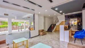 A spacious lobby with a marble floor, a staircase, and a seating area with a blue chair. - Everest Hotel Manali (Manali)