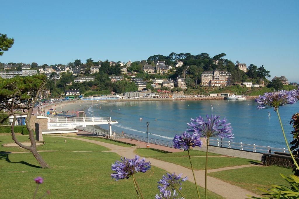 A coastal town with a beach, a bridge, and a row of houses.
