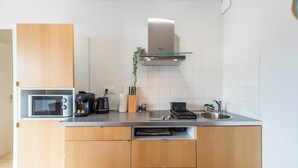 Een kleine keuken met een magnetron, koffiezetapparaat en een gootsteen.