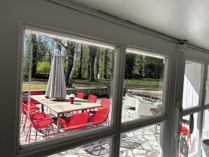 Un patio con una mesa y sillas, piso de piedra y vistas a árboles y un muro de piedra.