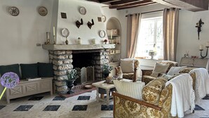 A traditional living room with a stone fireplace, patterned floor, and classic furniture.