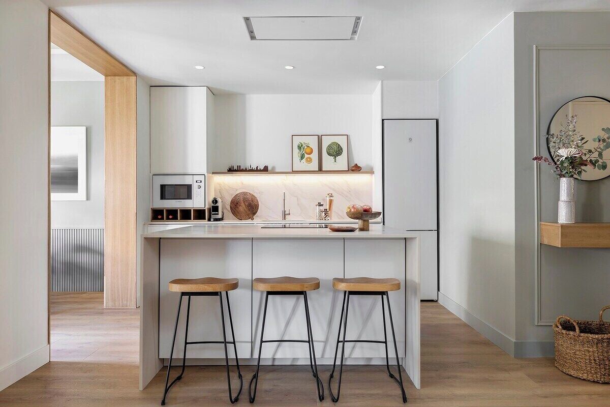 Une cuisine moderne dotée d’un îlot central, de tabourets de bar, d’un four à micro-ondes et d’un évier.