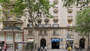 Un edificio de varios pisos con una entrada central, un letrero de estacionamiento y una pizzería en la planta baja.