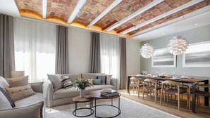 Una sala de estar moderna con techo de ladrillo, un conjunto de sofá, una mesa de comedor con sillas y lámparas colgantes.