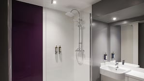 A modern bathroom with a glass shower enclosure, a white sink, and a large mirror.