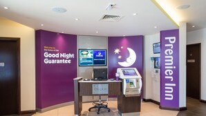 Un comptoir d’enregistrement équipé d’un ordinateur, d’un écran et d’un terminal en libre-service dans l’hôtel Premier Inn.