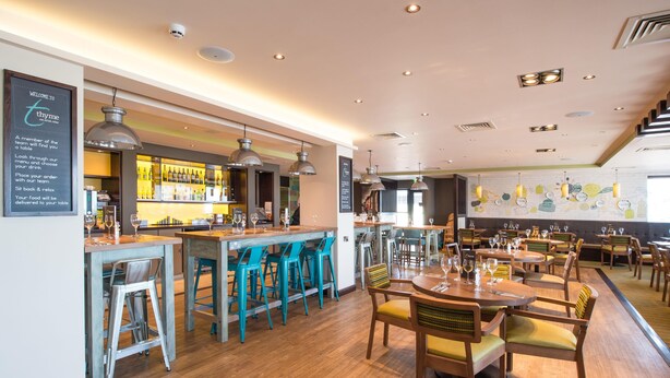 Un restaurant doté d’un bar, de plusieurs tables et de chaises.