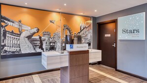Una recepción con un letrero de 'Premier Inn', un mural de paisaje urbano y un cartel que dice 'Estrellas brillando sobre mí'.