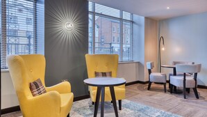 Una habitación con dos sillones amarillos, una mesa redonda, una lámpara de pie y vistas amplias por ventanas grandes.