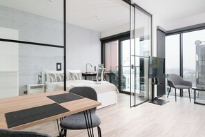 A modern hotel room with a large bed, a desk, a chair, and a TV. - RentPlanet - Apartament Prosta (Warsaw)