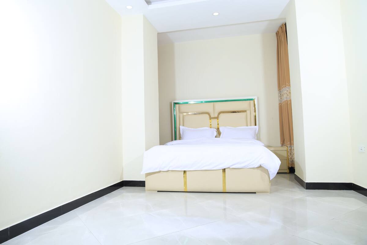 A hotel room with a large bed, a nightstand, and a mirror.