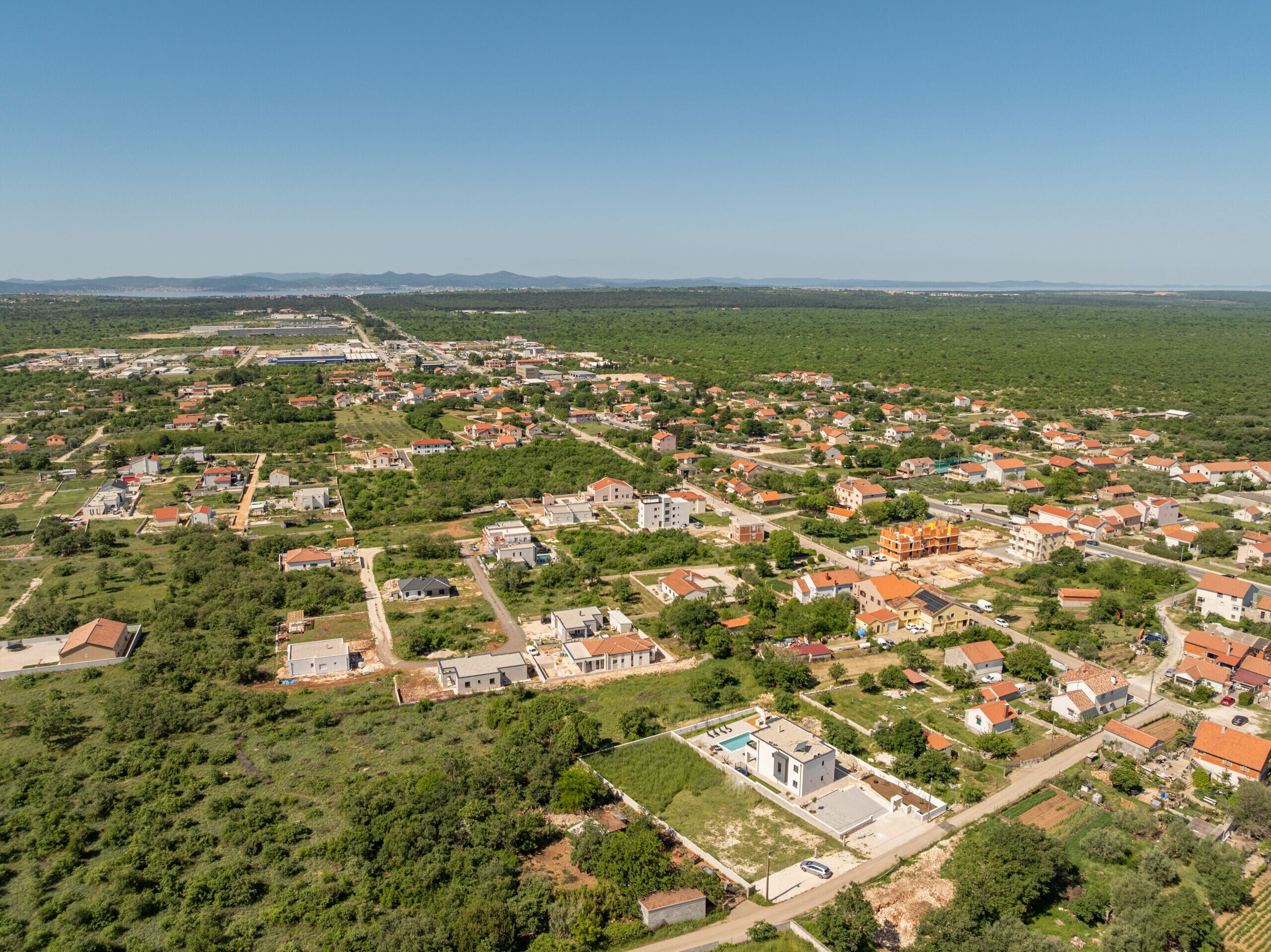 An aerial view of a residential area with houses, roads, and green spaces.