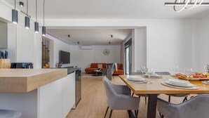 A modern kitchen with a wooden countertop, a dining area with a wooden table and chairs, and a living area with a sofa and a TV. - Villa Roma Murvica Zadarvillas (Policnik)