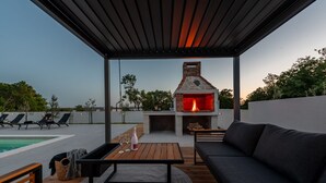 An outdoor patio with a brick oven, seating area, and pool. - Villa Roma Murvica Zadarvillas (Policnik)