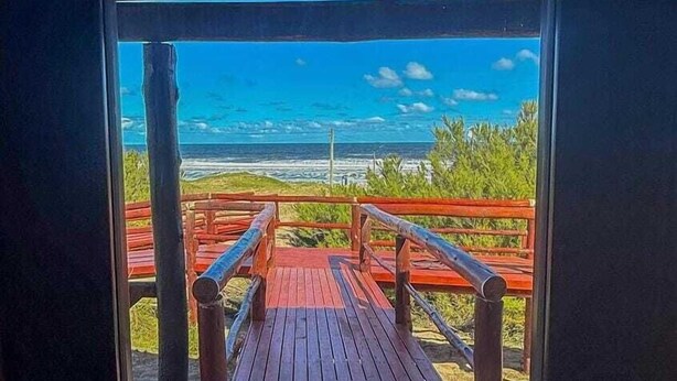 A wooden deck leading to a beach view with a railing. - AV366 (Arenas Verdes)
