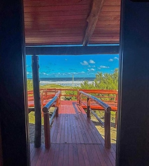 A wooden deck leading to a beach view with a railing.