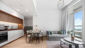 Eine moderne Küche mit Essbereich, einer Couch und Blick durch große Fenster.