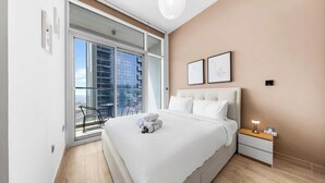 Ein modernes Hotelzimmer mit einem großen Bett, einem Nachttisch mit Lampe, Blick auf die Stadt durch raumhohe Fenster und einem Balkon mit einem Stuhl.