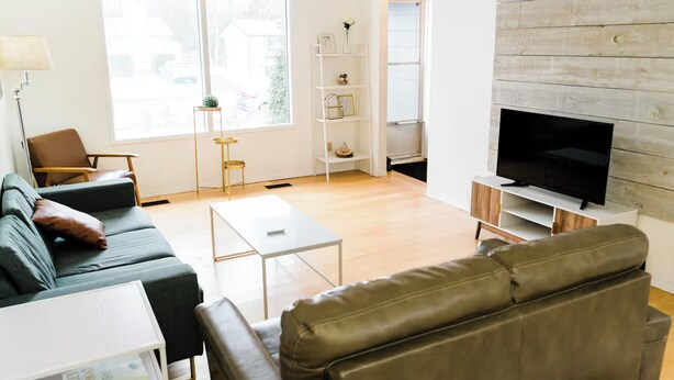 A modern living room with a sofa, coffee table, TV, and a bookshelf.