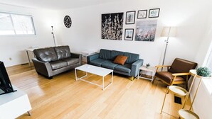 A modern living room with a leather sofa, a grey sofa, a white coffee table, a floor lamp, and a small side table.