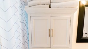 A bathroom with a white cabinet, a shower curtain with a chevron pattern, and a sink.