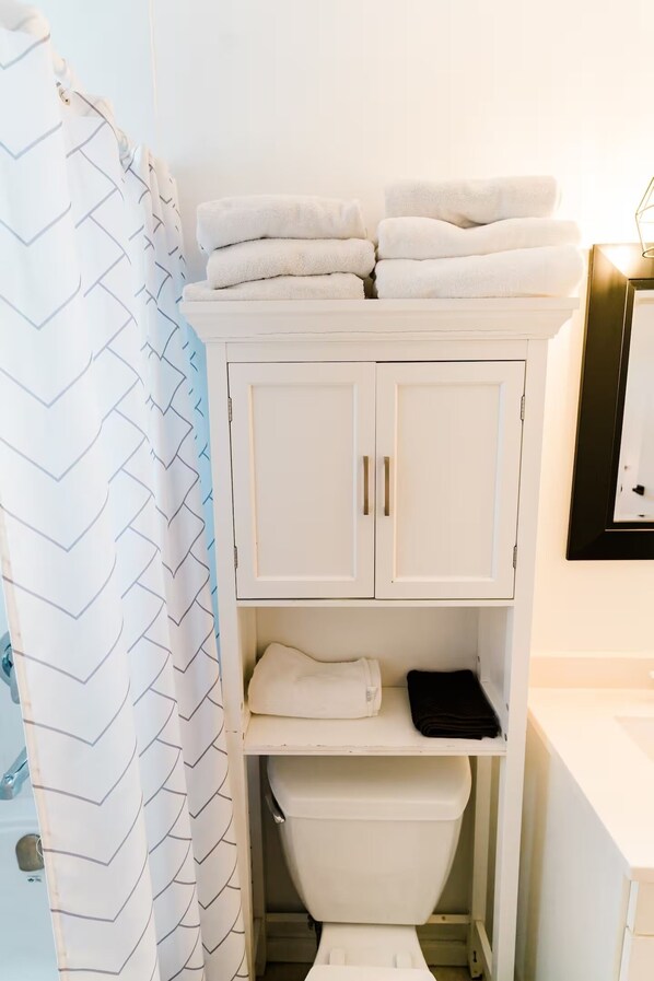 A bathroom with a white cabinet, a shower curtain with a chevron pattern, and a sink.