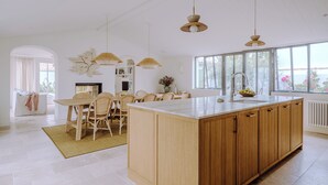A modern kitchen with a central island, wooden cabinets, and pendant lighting.