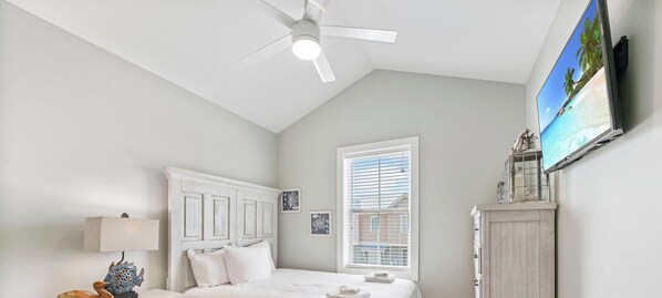 A bedroom with a bed, a nightstand, a dresser, a ceiling fan, and a window.